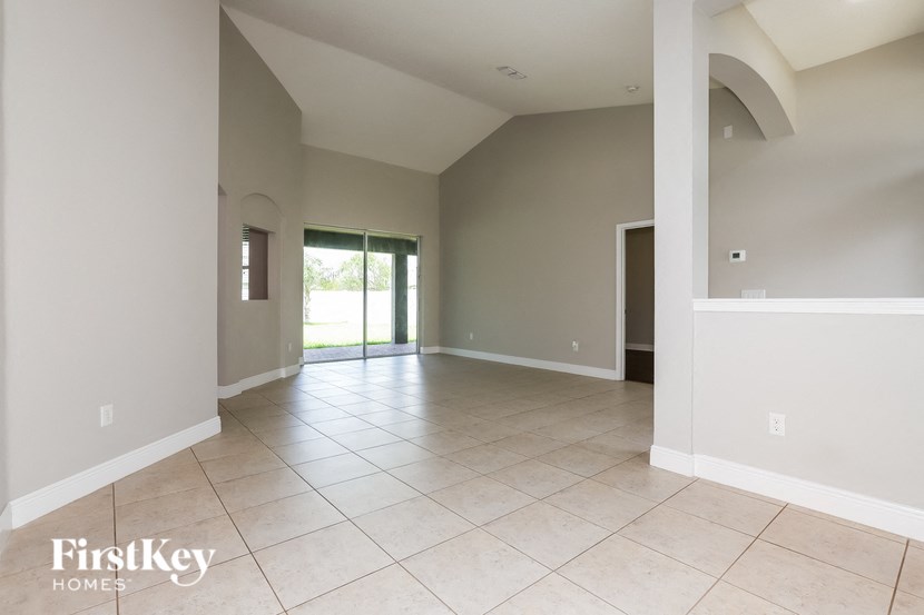 an empty living room with tiled flooring and a door to a patio