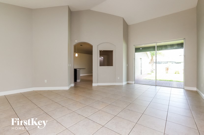 an empty living room with a large tiled floor and a door to a patio
