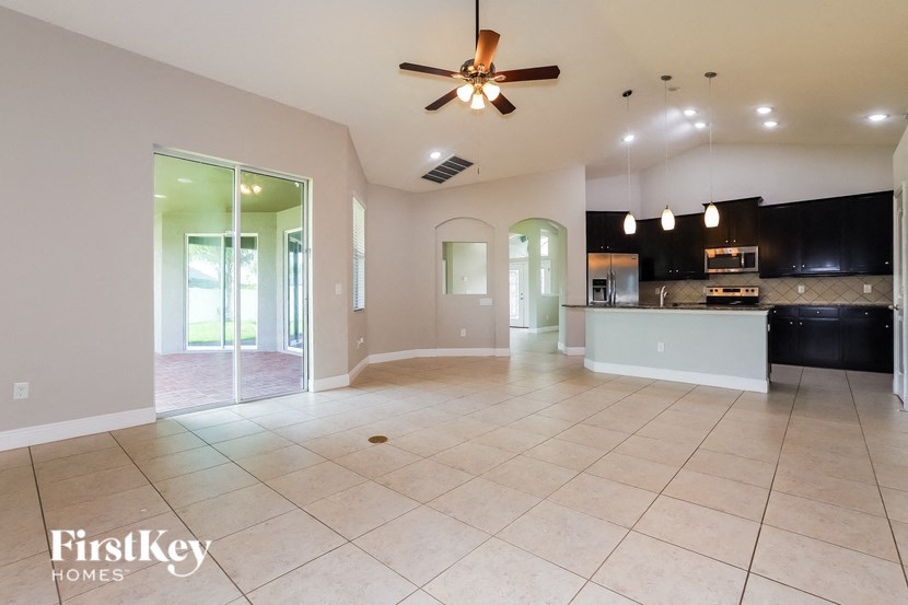 an open kitchen and living room with tile flooring and a ceiling fan