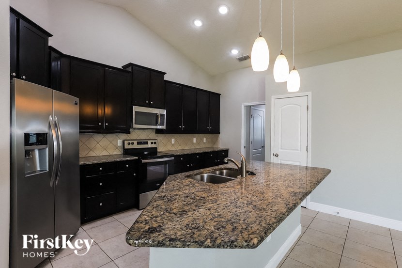 a kitchen with granite counter tops and black cabinets and stainless steel appliances