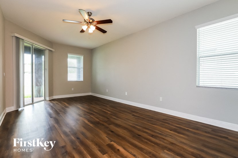 an empty living room with wooden floors and a ceiling fan