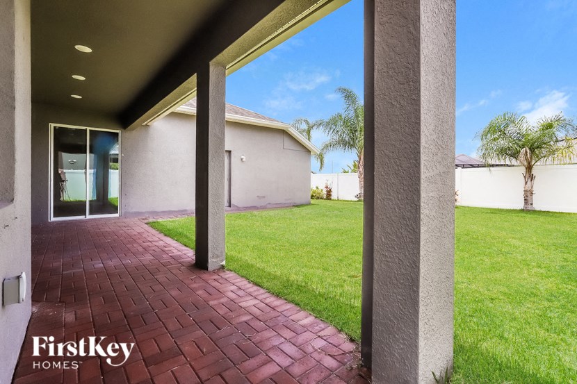 a red brick walkway leading to a house with a yard and grass