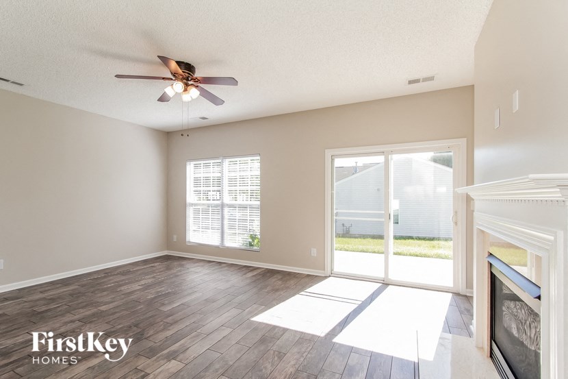 an empty living room with a ceiling fan and a sliding glass door