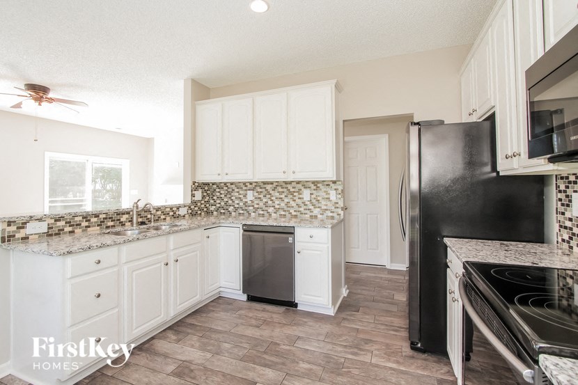 a kitchen with white cabinets and a black refrigerator