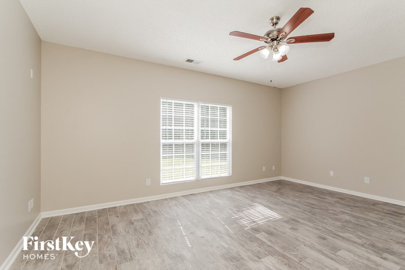 an empty living room with a ceiling fan and a window