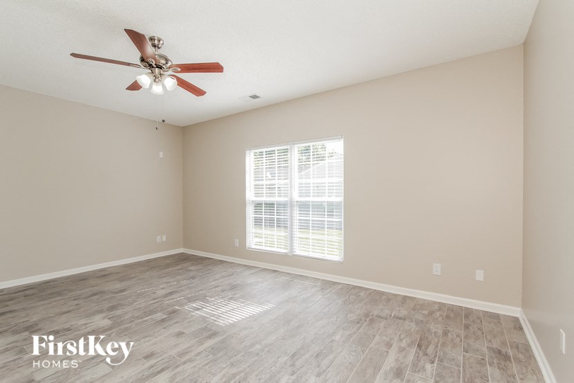 an empty living room with a ceiling fan and a window