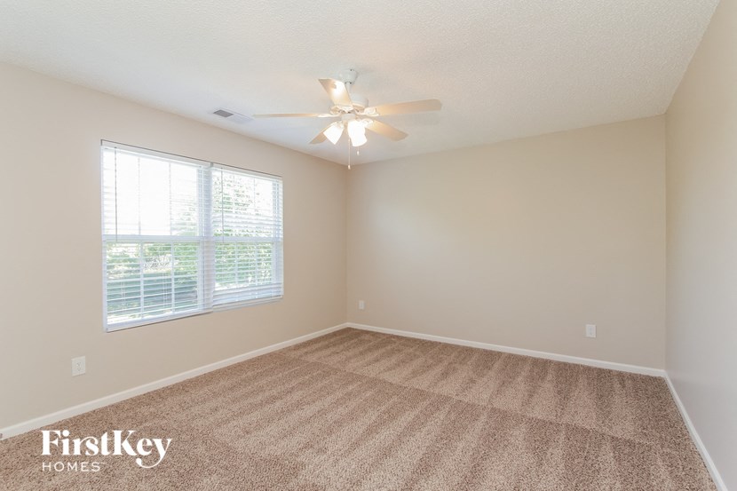 an empty living room with a ceiling fan and a window