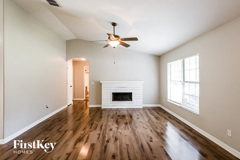 A spacious room with a fireplace and a ceiling fan.