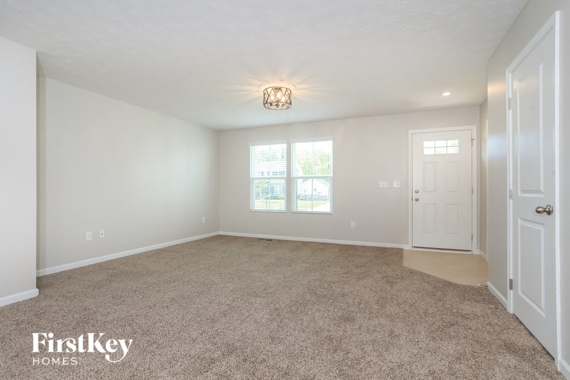 a spacious living room with carpet and a white door
