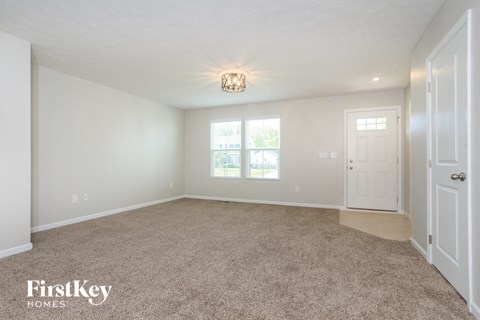 a spacious living room with carpet and a white door