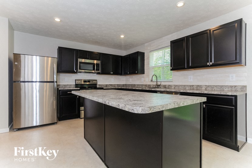 a kitchen with black cabinets and a marble counter top