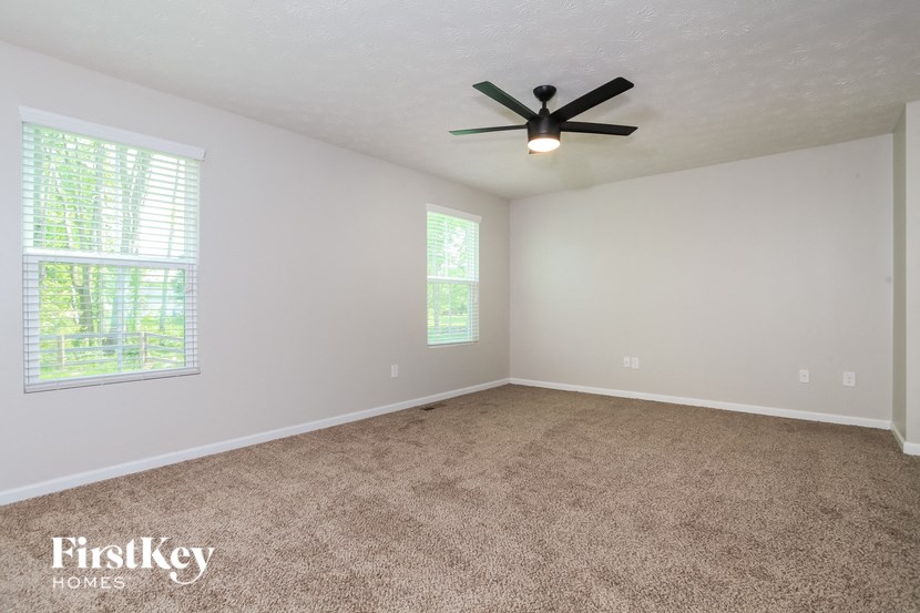 the spacious living room with carpeting and a ceiling fan