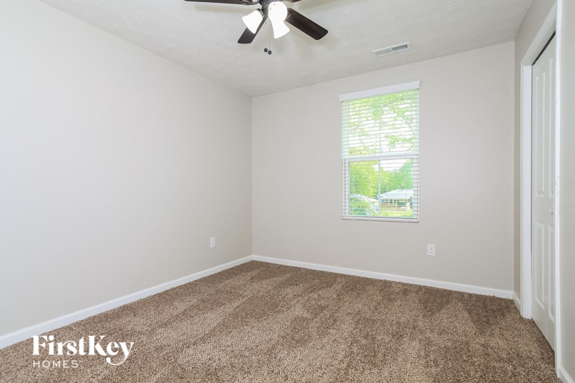 the living room of an empty house with carpet and a ceiling fan