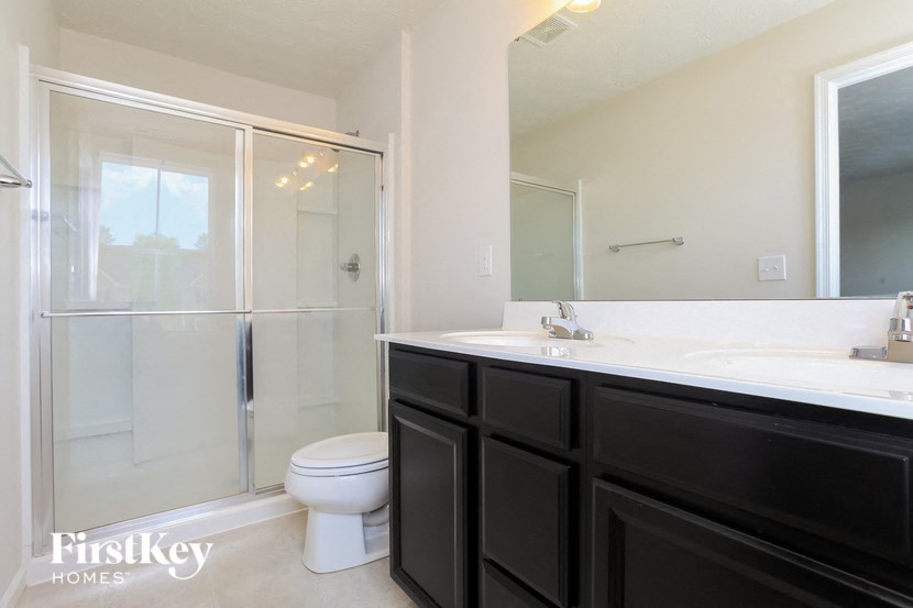 a bathroom with a shower toilet and sink and black cabinets