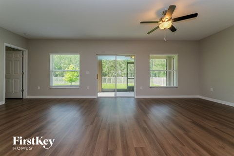 A spacious room with wooden floors and a ceiling fan.