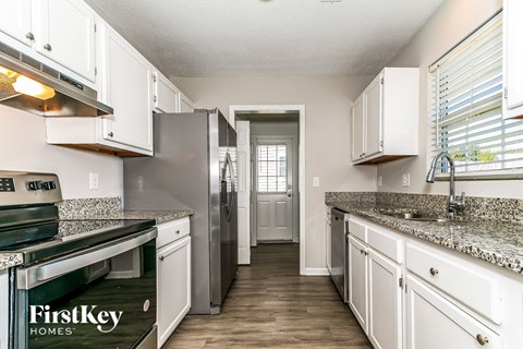 A kitchen with white cabinets and a granite countertop.
