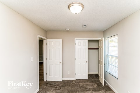 A room with two white doors and a window with blinds.