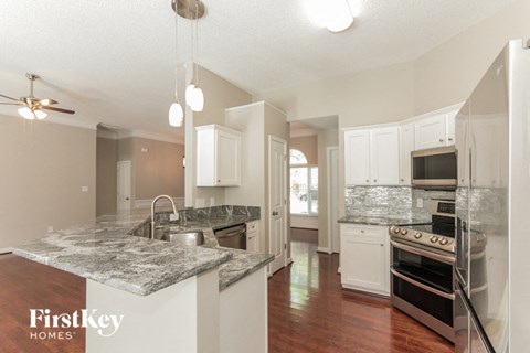 A kitchen with a marble countertop and a stove top oven.