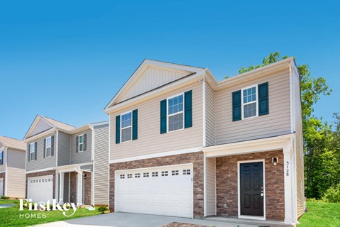a beige house with a garage and a blue sky