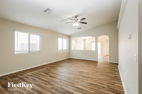 A spacious room with wooden floors and a ceiling fan.