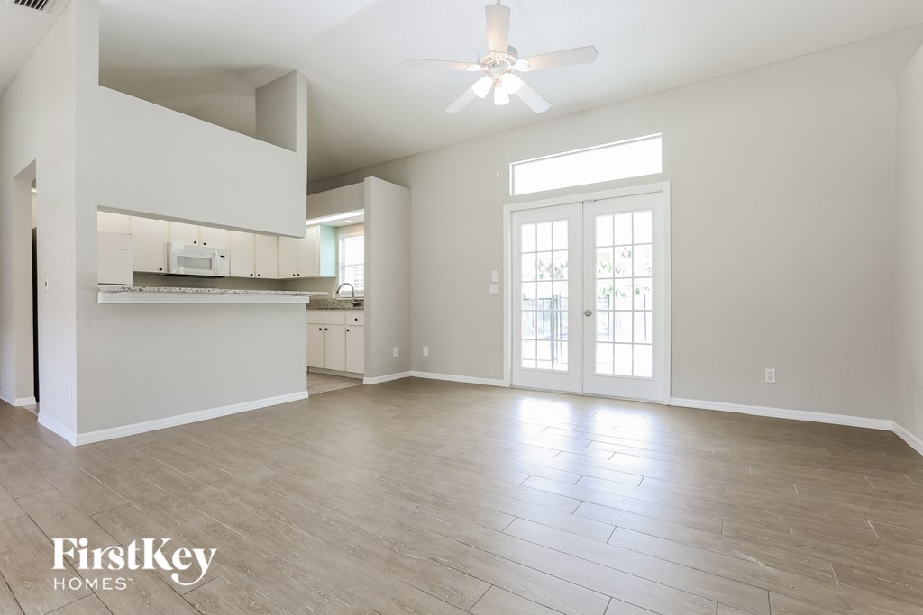 A spacious living room with a ceiling fan and lighting fixture.