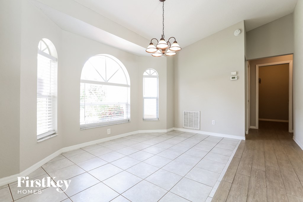 A spacious room with a chandelier and large windows.