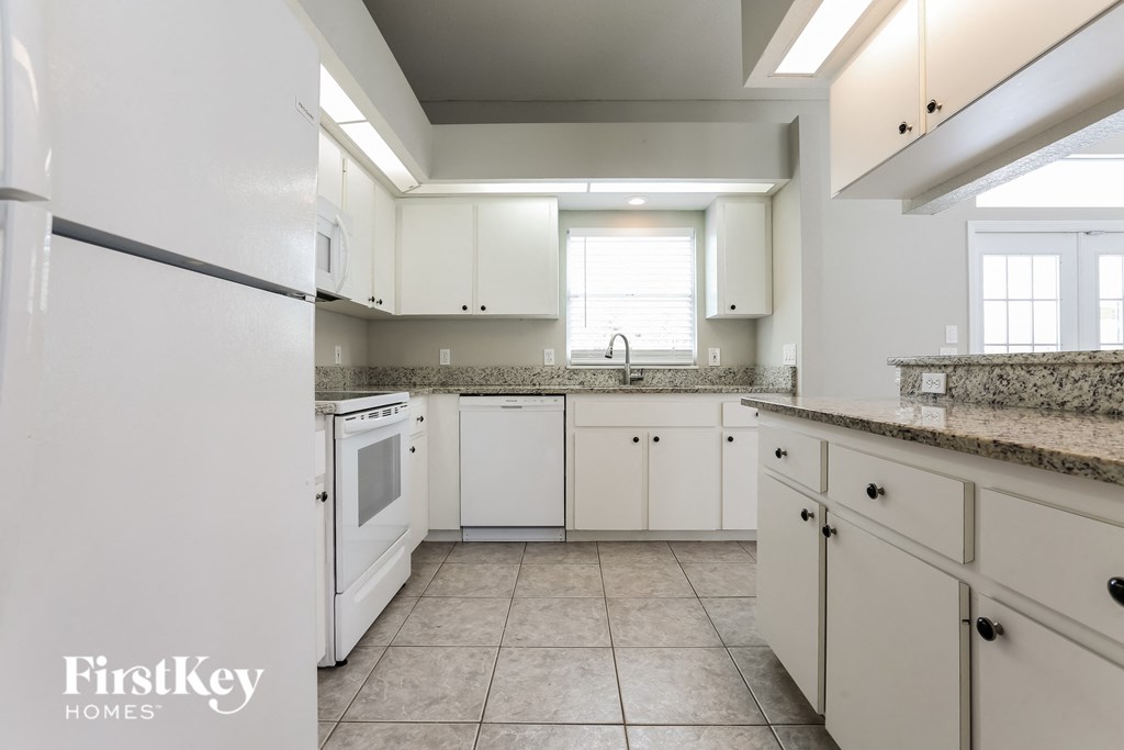A kitchen with white appliances and cabinets.