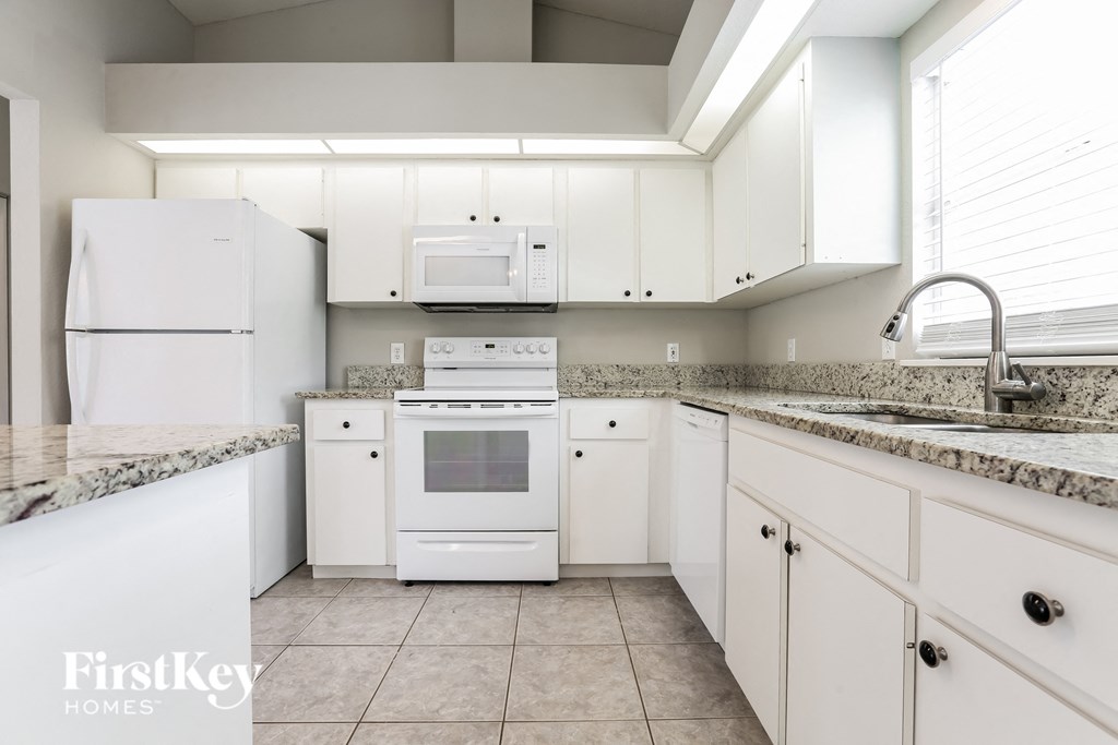 A kitchen with white appliances and cabinets.