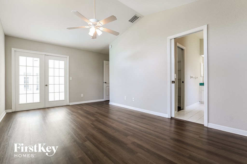 A room with a ceiling fan and wooden floors.