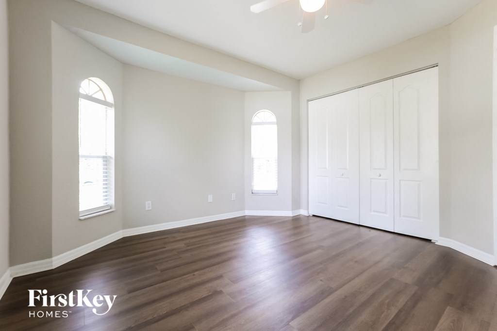 A spacious room with wooden floors and a ceiling fan.