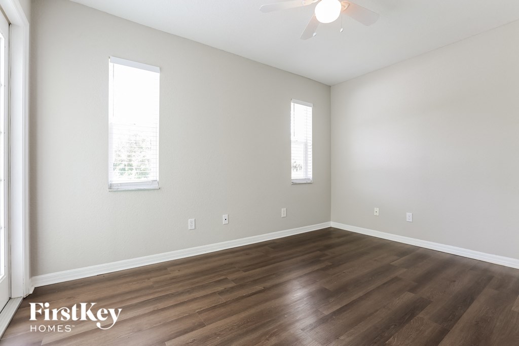 A room with wooden flooring and two windows.