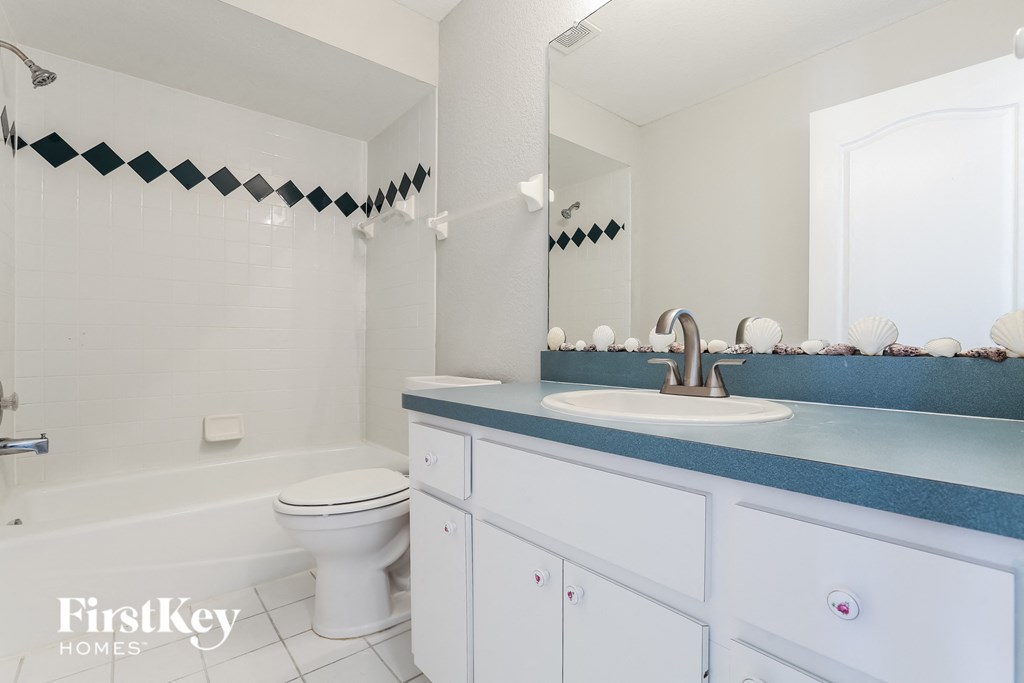 A white bathroom with a black and white tile border on the shower.