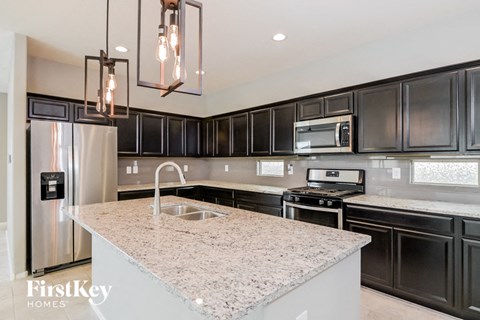 A modern kitchen with a granite countertop and stainless steel appliances.