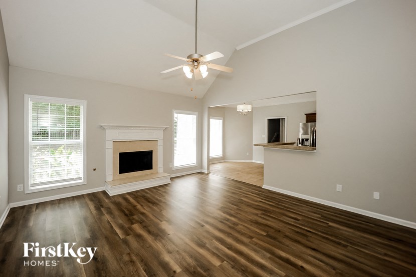 an empty living room with a ceiling fan and a fireplace
