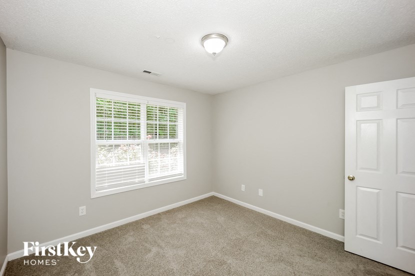 the bedroom of a home with a large window and carpet