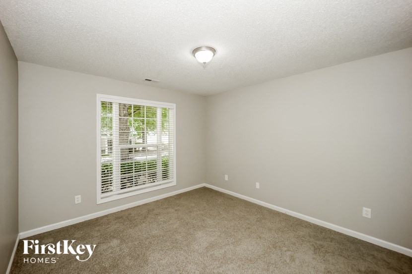 a bedroom with a large window and a carpeted floor