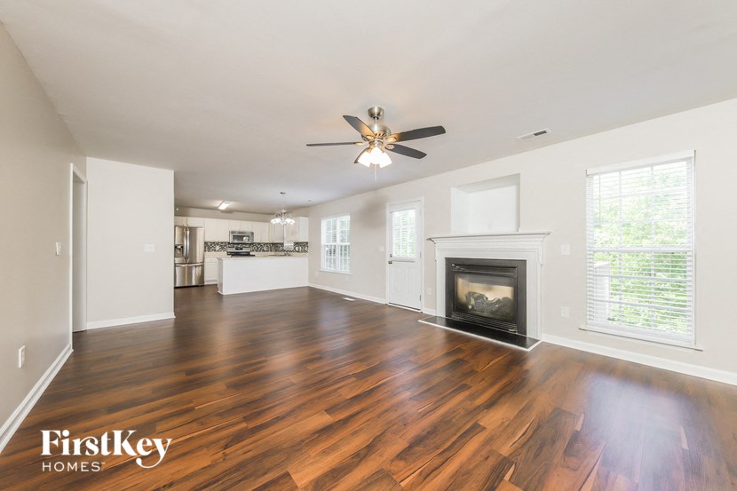 an empty living room with a fireplace and a ceiling fan