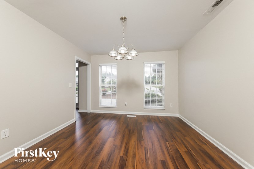 an empty living room with wood flooring and a chandelier