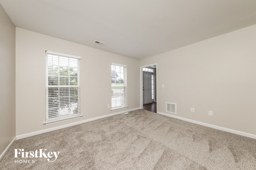 an empty living room with two windows and a door