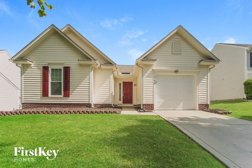 a beige house with a red door and a driveway