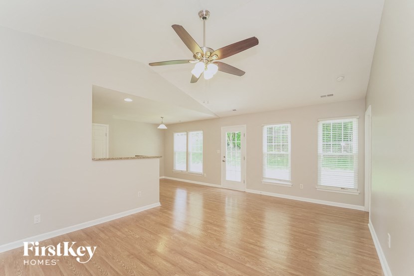 an empty living room with a ceiling fan and a window