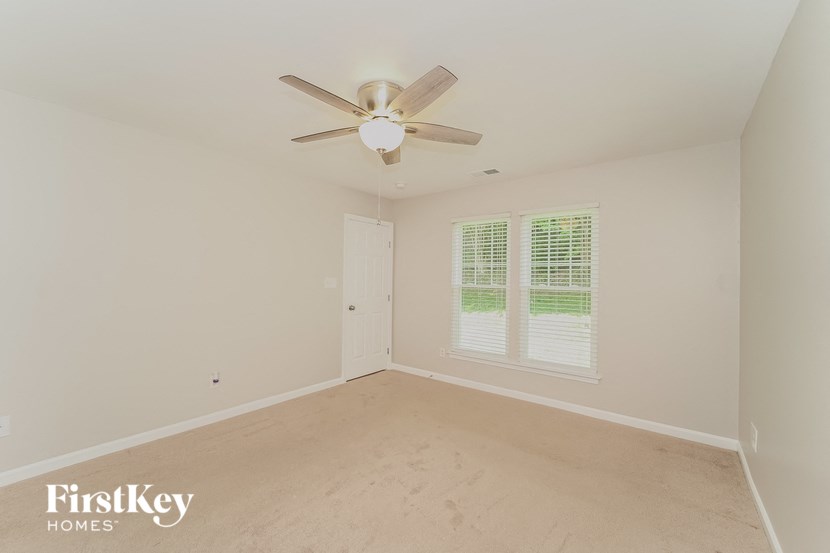 an empty living room with a ceiling fan and a window