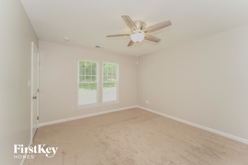 an empty bedroom with a ceiling fan and a window