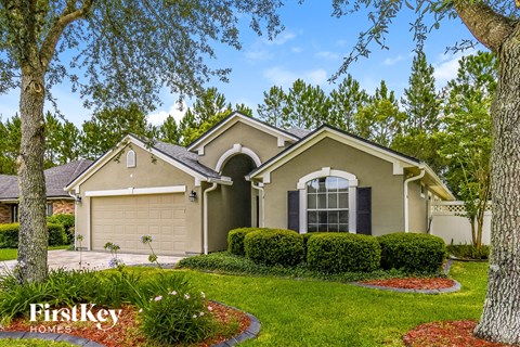 A house with a well-manicured lawn and trees in the background.