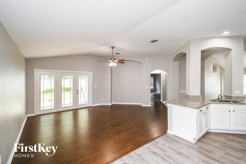 A spacious kitchen and living room with a ceiling fan and hardwood floors.