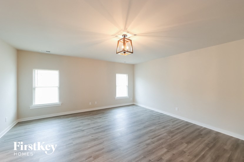 A room with wooden floors and two windows.