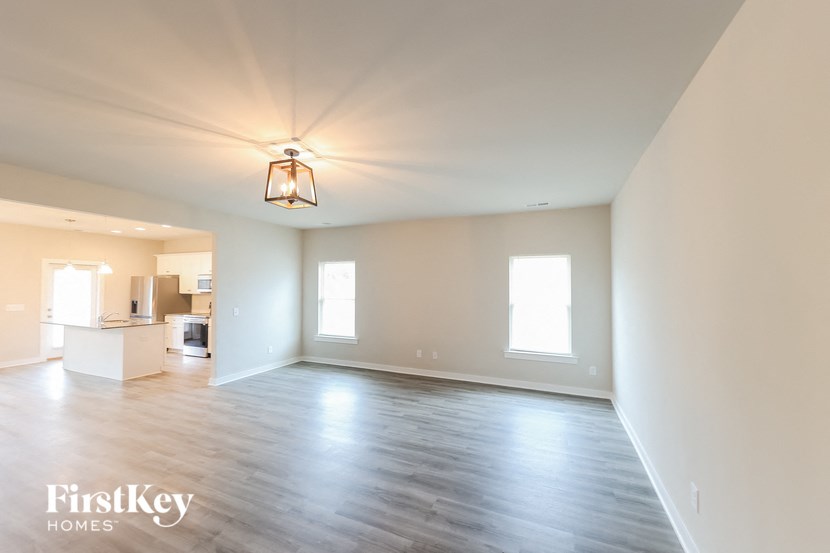 A large empty room with wooden floors and a hanging light fixture.