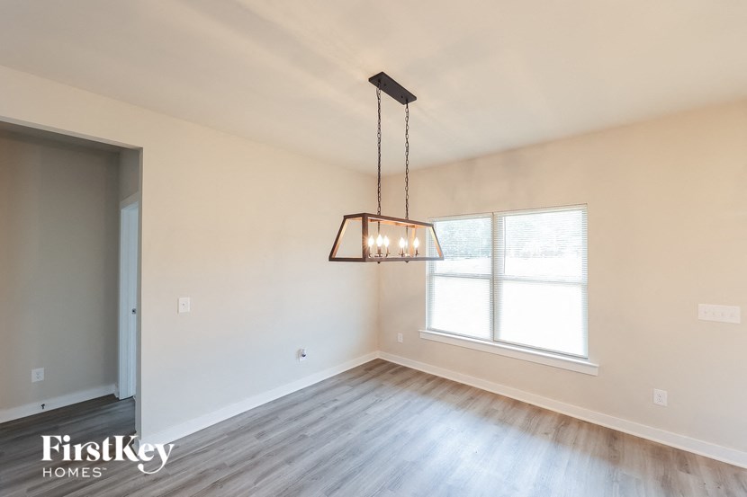 A room with a light hanging from the ceiling and a window letting in light.