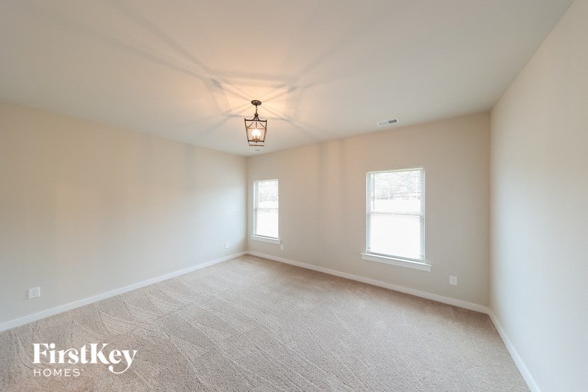 A room with a carpeted floor and two windows.