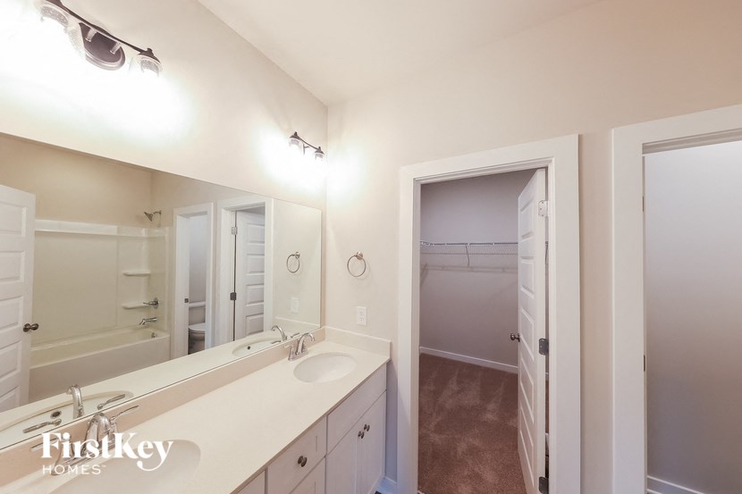 A bathroom with a sink, mirror, and a shower.